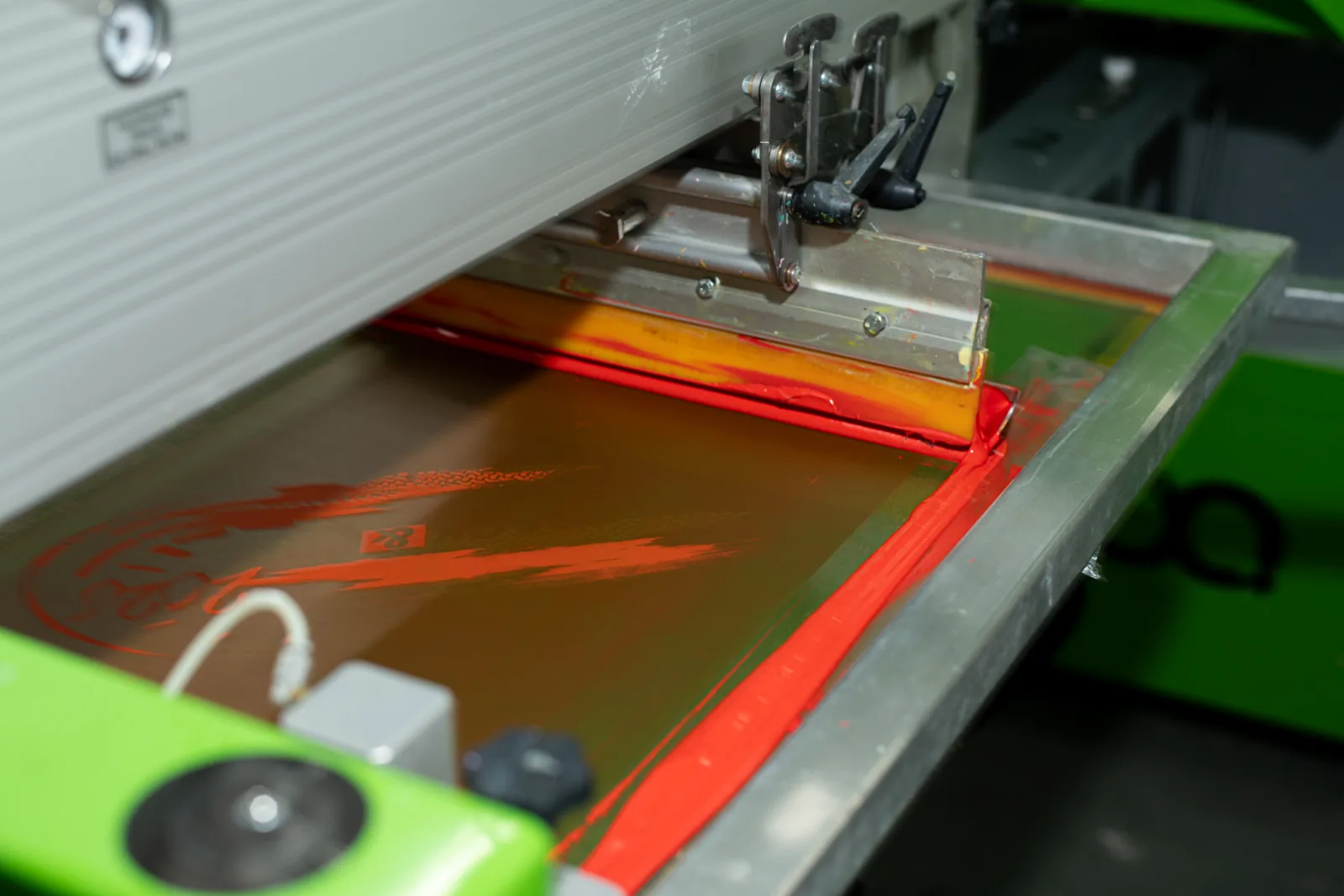 Siebdruck mit Rakel und roter Druckfarbe auf dem Sieb, TIME/LESS Prints.