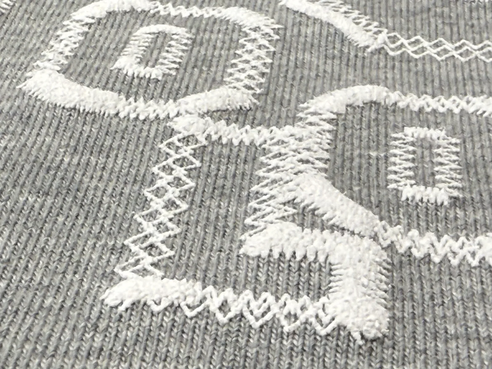 Weißer Puff-Druck auf grau meliertem Sweatstoff mit plastischem Relief, TIME/LESS Prints Hannover.