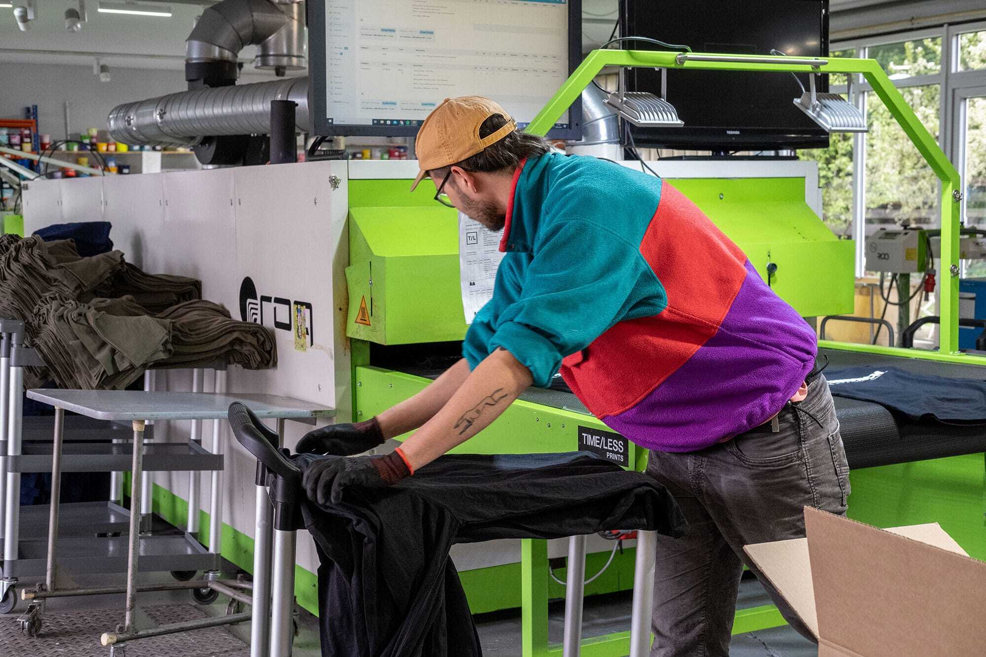 Person beim Falten von fertig bedruckten T-Shirts.
