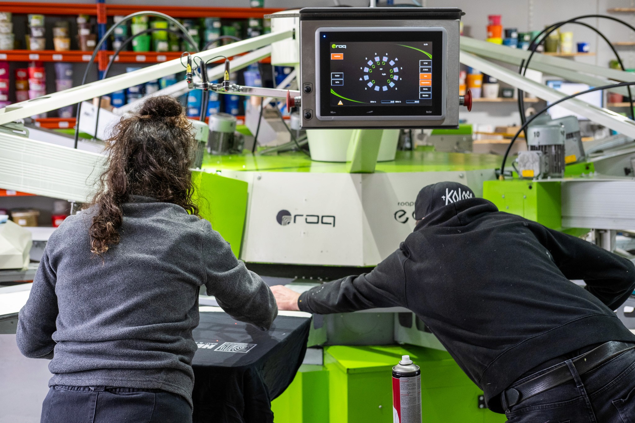 Zwei Personen bei der Siebdruckproduktion von Eventtextilien bei TIME/LESS Prints in Hannover.
