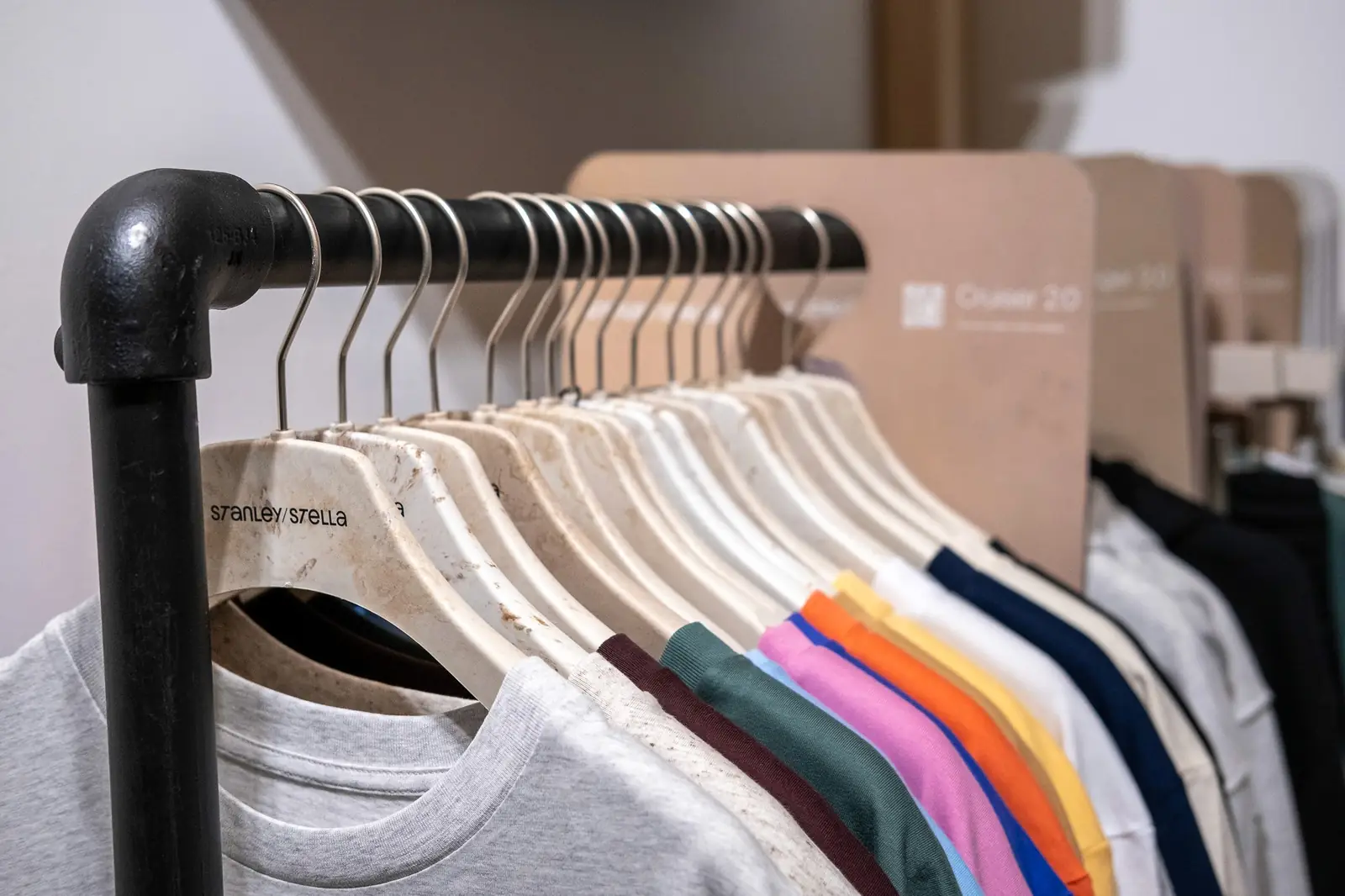 Bunte T-Shirts hängen auf Bügeln im Showroom von TIME/LESS Prints.