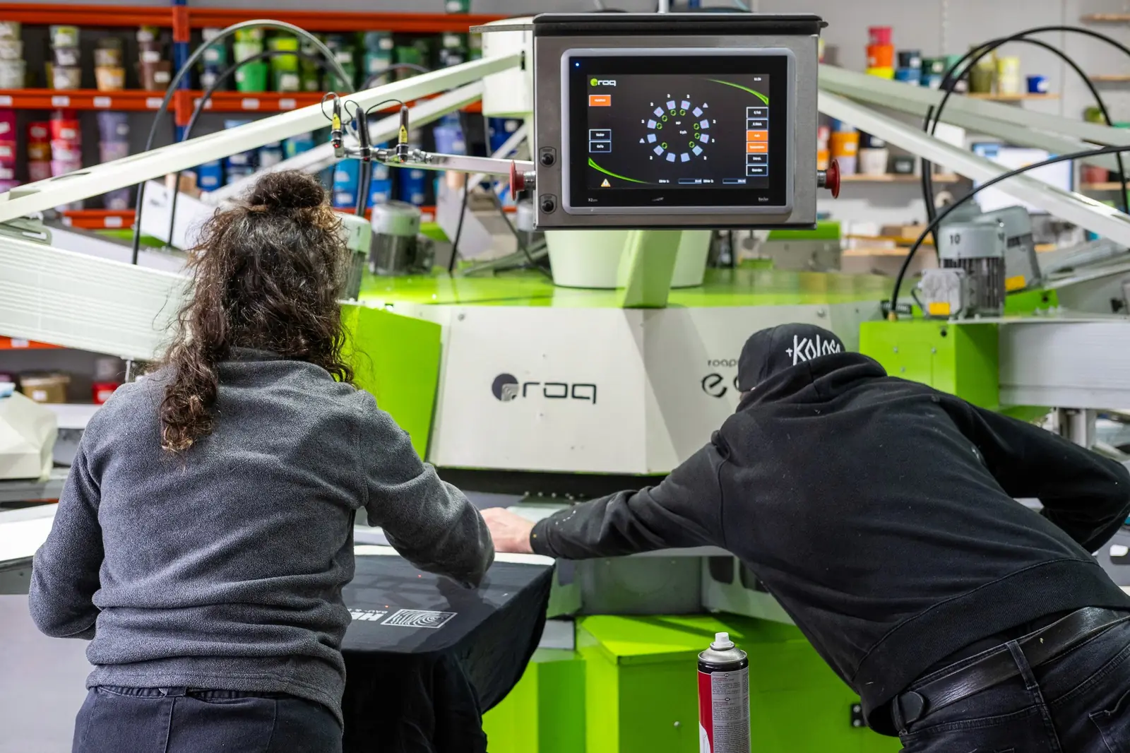Zwei Personen bedienen eine Siebdruckmaschine.