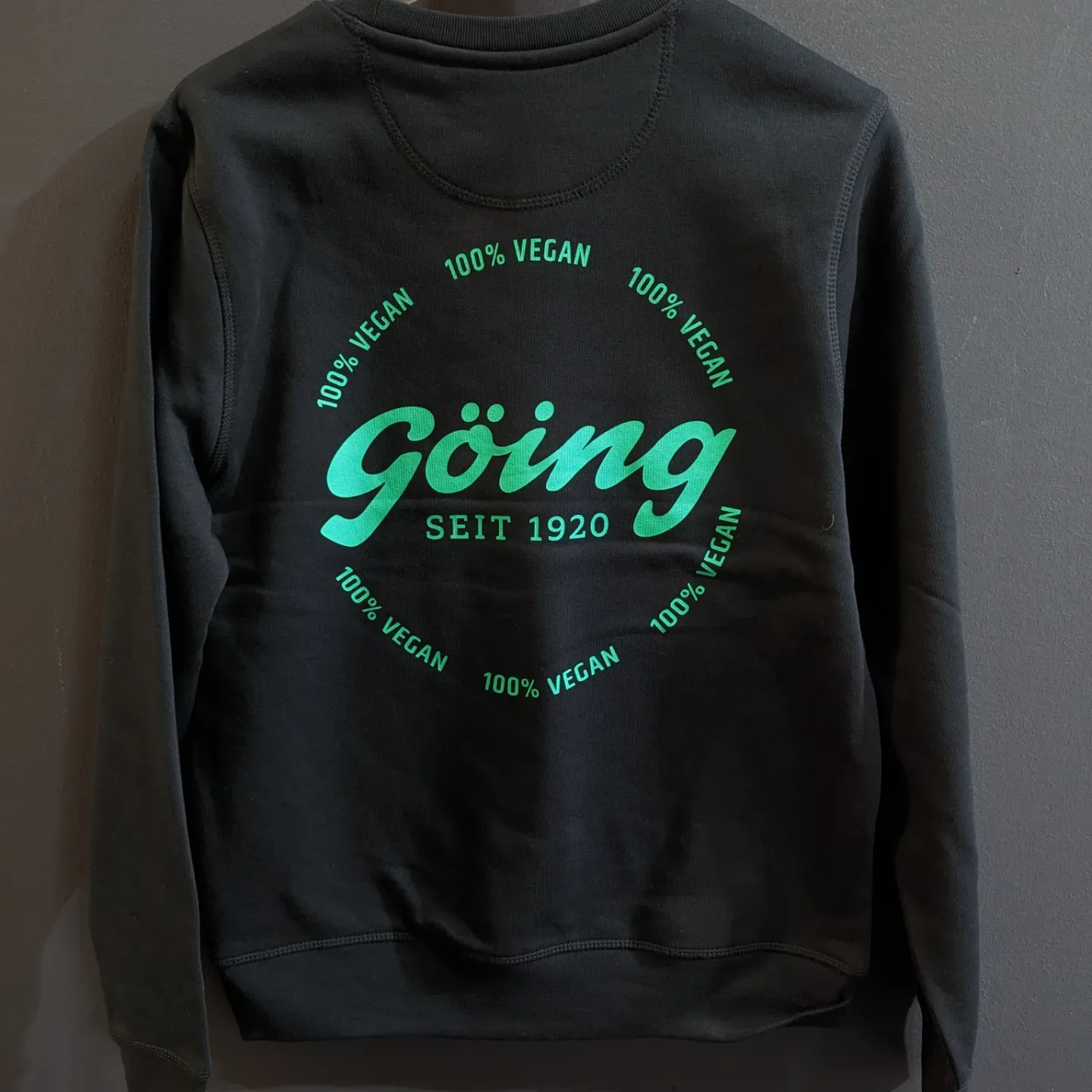 Dunkles Sweatshirt mit grünem Firmenlogo als Rückenprint im Siebdruck bei TIME/LESS Prints.