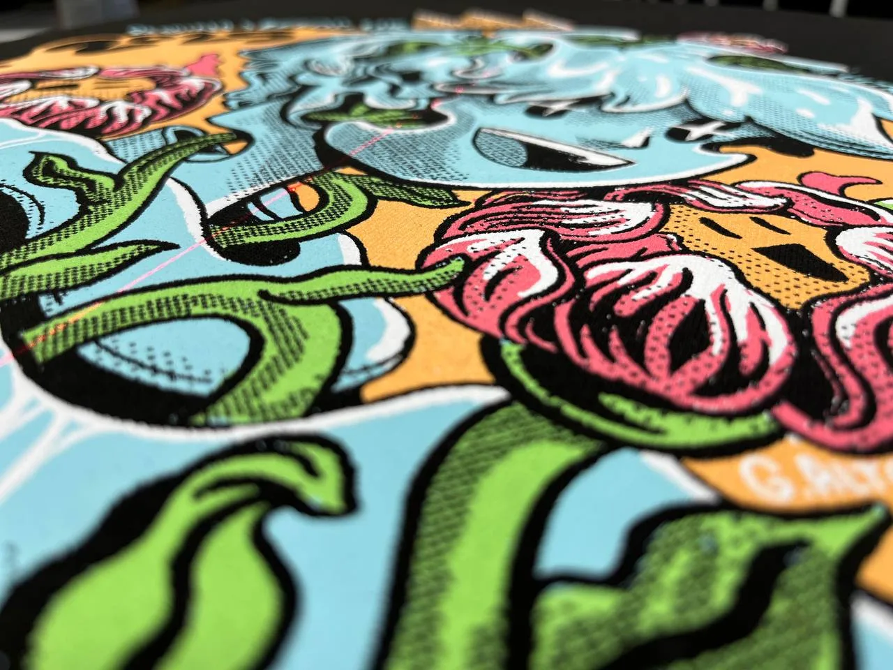 Detailaufnahme einer mehrfarbigen Illustration mit Rastern in Türkis, Pink und Grün im Siebdruck auf schwarzem Shirt bei TIME/LESS Prints.
