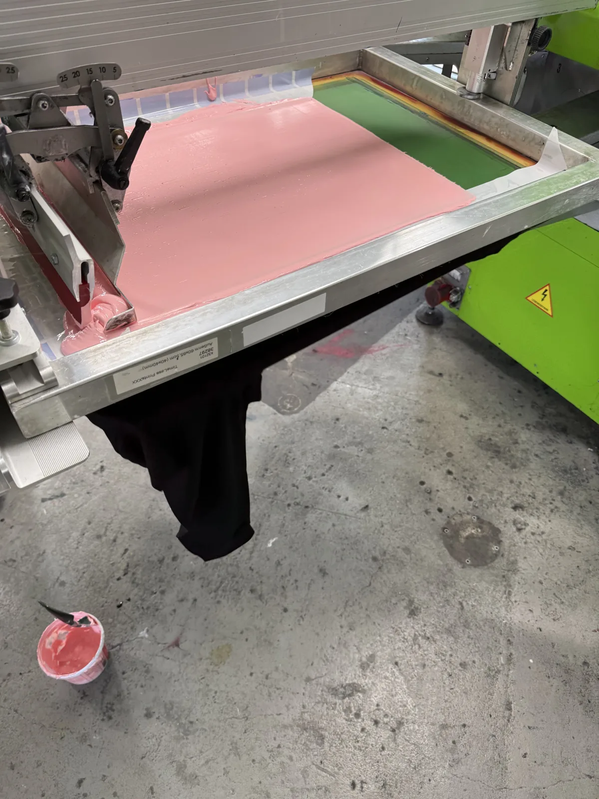 Siebdruckrahmen mit rosa Farbe auf der Druckmaschine beim Einrichten eines Auftrags bei TIME/LESS Prints.