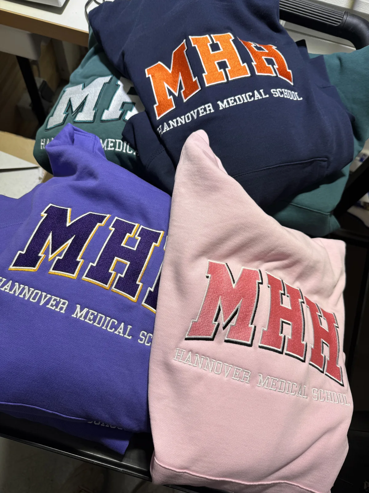 Sweatshirts in Rosa, Lila, Navy und Grün mit gesticktem College-Schriftzug, Maschinenstick bei TIME/LESS Prints.